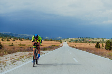 Full length portrait of an active triathlete in sportswear and with a protective helmet riding a bicycle. Selective focus 