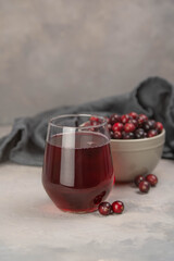 Glass with healthy cranberry juice on light background