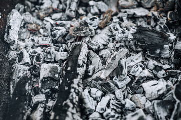 Close-up photo of smoldering gray coals, burnt ash close-up in a campfire.