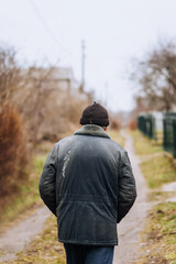 A lonely man in dirty torn clothes, a beggar tramp, an old bum walks on the street in search of food and shelter. Photography, the concept of the problems of humanity, lifestyle.