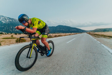 Full length portrait of an active triathlete in sportswear and with a protective helmet riding a...