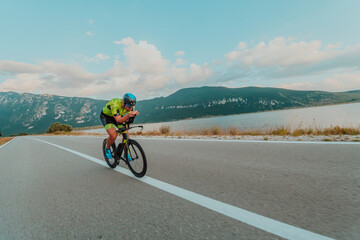 Full length portrait of an active triathlete in sportswear and with a protective helmet riding a...