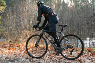 Fototapeta na wymiar Professional cyclist in sportswear and helmet rides on a trail in the autumn forest.