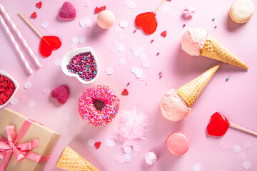 Romantic sweet dessert table with pink waffles, donut, ice cream, macaron, lollipop, candies. Valentine's day concept. Top view.