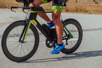 Close up photo of an active triathlete in sportswear and with a protective helmet riding a bicycle. Selective focus