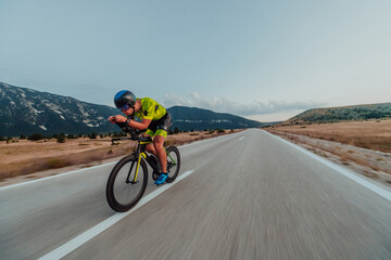 Full length portrait of an active triathlete in sportswear and with a protective helmet riding a...