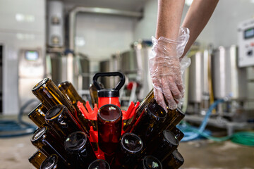 Female brewer in a craft brewery with beer bottles.