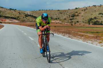 Full length portrait of an active triathlete in sportswear and with a protective helmet riding a...