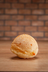 Cheese bread on wooden table and bricks wall background.