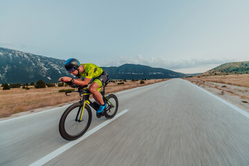 Full length portrait of an active triathlete in sportswear and with a protective helmet riding a...