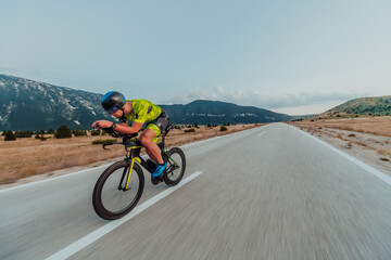 Full length portrait of an active triathlete in sportswear and with a protective helmet riding a bicycle. Selective focus 