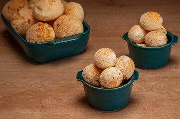 Cheese breads in a green ramekin on wooden table and bricks wall background.