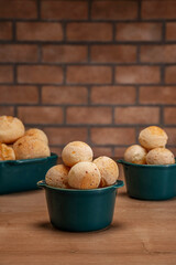 Cheese breads in a green ramekin on wooden table and bricks wall background.