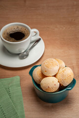 Cheese breads in a green ramekin with a cup of coffee on wooden table.