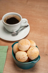 Cheese breads in a green ramekin with a cup of coffee on wooden table. - obrazy, fototapety, plakaty