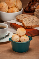 Cheese breads in a green ramekin with a cup of coffee on wooden table.