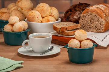 Cheese breads in a green ramekin with a cup of coffee on wooden table and bricks wall background.
