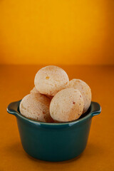 Isolated cheese breads in a green ramekin on orange background.