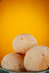 Isolated cheese breads in a green ramekin on orange background.