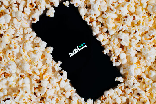 Shahid tv mobile application on smartphone lying in pile of popcorn, top view. Online movies and series concept. Astana, Kazakhstan 25.01.2023