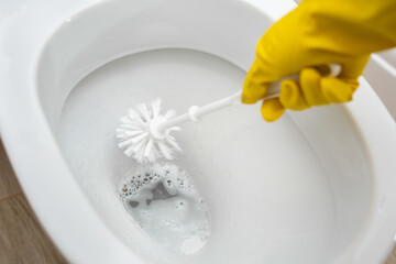 Cleaning and disinfection of toilets. Cleaner in yellow rubber gloves cleans the toilet with a brush