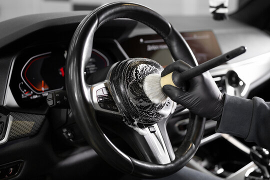 Worker wipes the steering wheel of the car, dry cleaning and interior washing. Detailing studio.