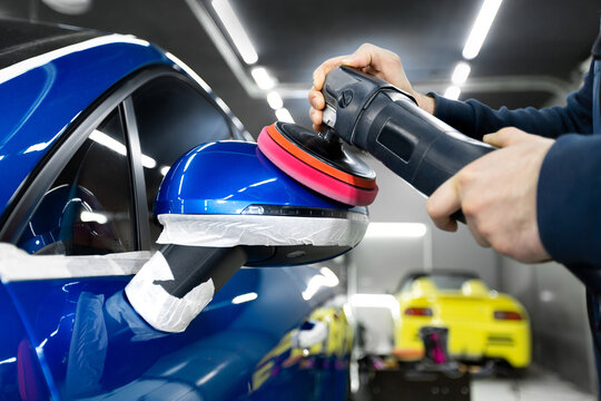 Professional detailing a car in car studio, hands with orbital polisher, scratching remover, vehicle care concept.