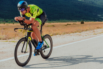 Naklejka premium Full length portrait of an active triathlete in sportswear and with a protective helmet riding a bicycle. Selective focus 
