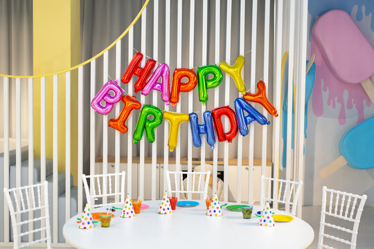 A HAPPY BIRTHDAY phrase made of multicolored balloon letters in a decorated room.