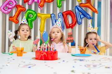 Group of children with pipes, funny inscriptions and masks are having fun at a birthday party.
