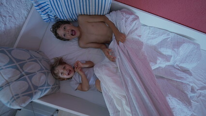Fototapeta na wymiar Happy children in morning bed. Cute little boy getting up from bedsheets. Two brothers hanging out