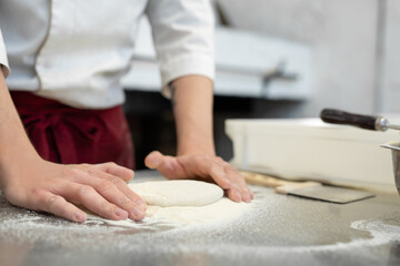 Obraz na płótnie Canvas The process of preparing pizza, a person rolls out the dough with his hands.