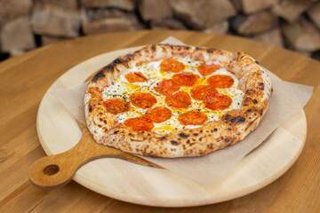 Ready-made Italian pizza on a wooden plate is ready to be served in the restaurant.