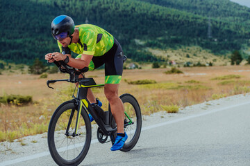 Full length portrait of an active triathlete in sportswear and with a protective helmet riding a bicycle. Selective focus 