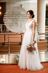 Naklejka premium portrait of a beautiful bride against the background of a chandelier in the shape of a ball