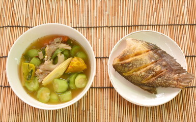 boiled spicy mixed vegetable curry soup on bowl with deep fried snake skin catfish or gourami on dish