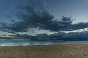 Evening wide view from the beach to the sea with clouds in the background