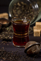 Brewed tea is poured into a cup on a black background. traditional tea
