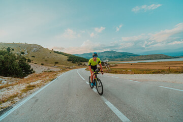 Full length portrait of an active triathlete in sportswear and with a protective helmet riding a...
