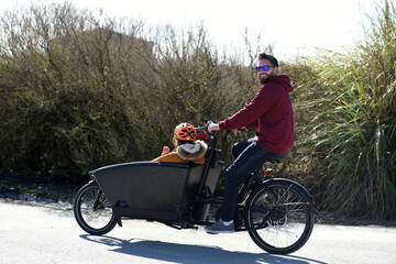 man carrying two children on a bicycle