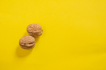 Top view of dried walnuts on yellow background with copy space
