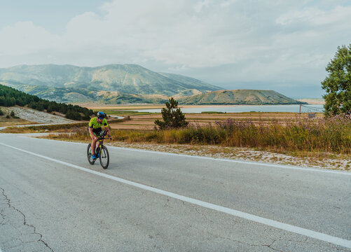 Full length portrait of an active triathlete in sportswear and with a protective helmet riding a bicycle. Selective focus 