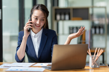 Attractive Asian businesswoman doing business related to village building project contacting using a mobile phone to chat and Negotiate management ideas in her office.