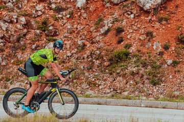 Full length portrait of an active triathlete in sportswear and with a protective helmet riding a...
