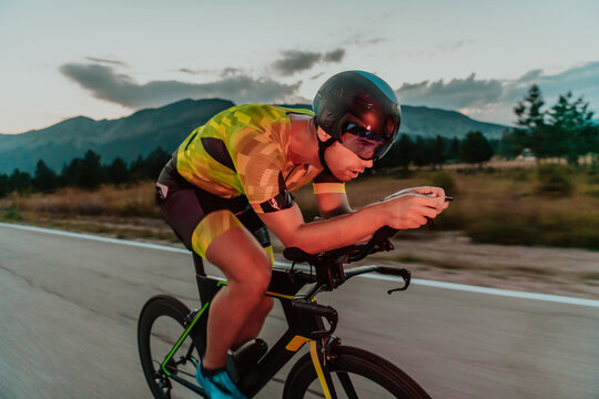 Night drive. Full length portrait of an active triathlete in sportswear and with a protective helmet riding a bicycle in night time.. Selective focus © .shock