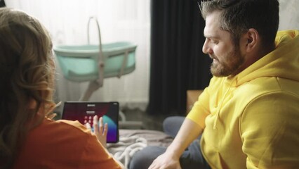 Happy parents are talking, laughing and looking at baby photos. A couple imagines the future meeting with their child. High quality 4k footage