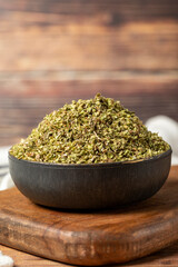 Dried thyme leaves. Thyme spice in a bowl on a wooden background. Dry spice concept. Close up