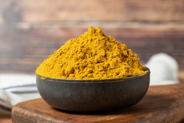 Curry Masala Powder. Turmeric powder or curry powder spice in a bowl on wooden background. İndian spices. Dry spice concept. close up