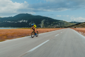 Full length portrait of an active triathlete in sportswear and with a protective helmet riding a...