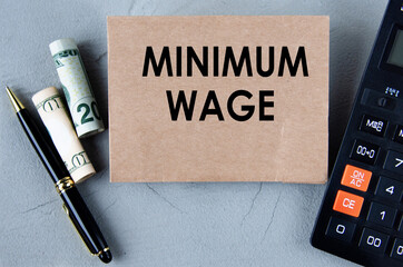 MINIMUM WAGE - words on brown paper on the background of a calculator, banknotes and pen